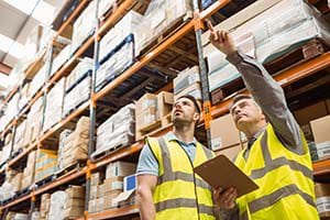 Warehouse managers using integrated wholesale distribution software to manage inventory.